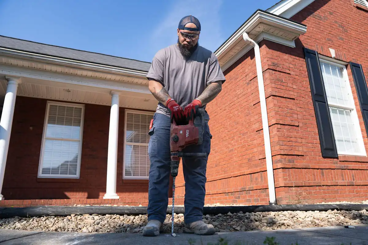 Certified Foundation Specialist drilling holes in a sidewalk