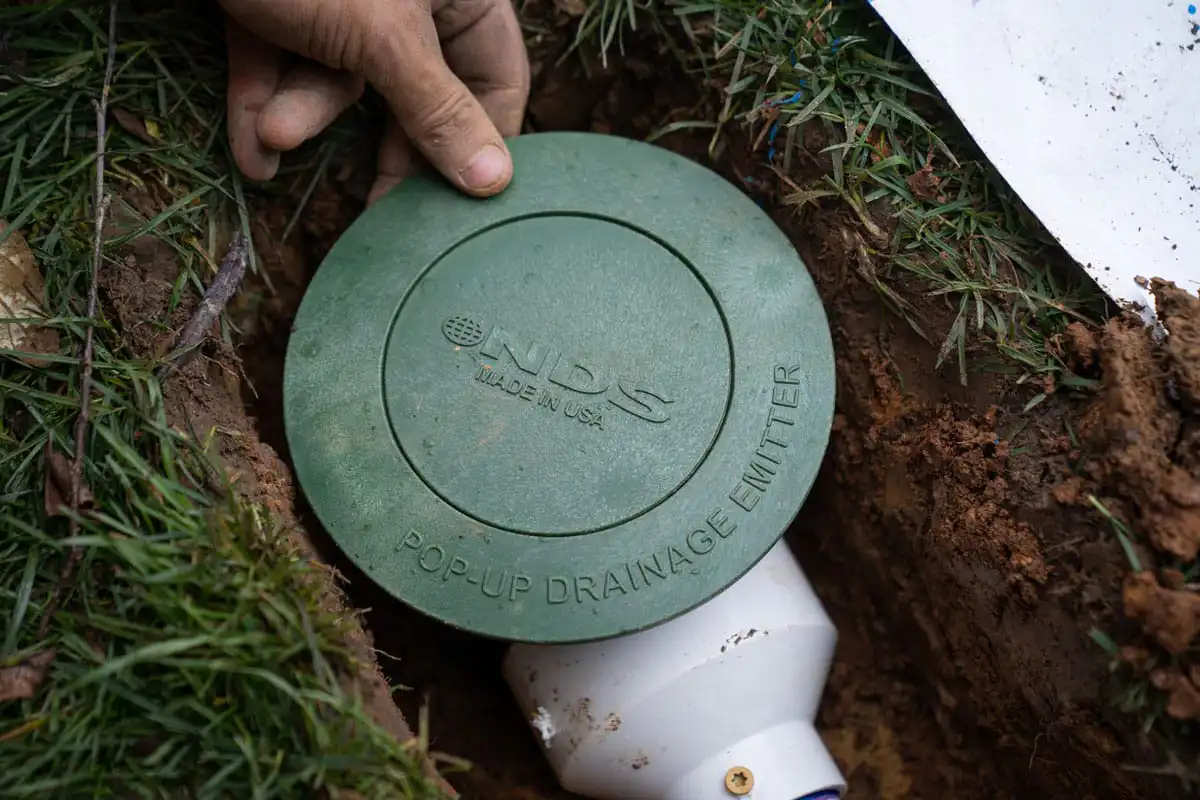 Crawl space waterproofing discharge NDS drainage emitter in a yard