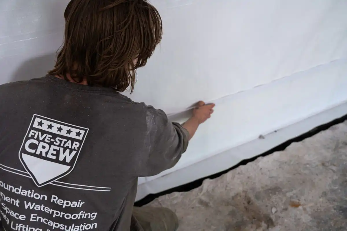 Top cap being installed on a basement vapor barrier