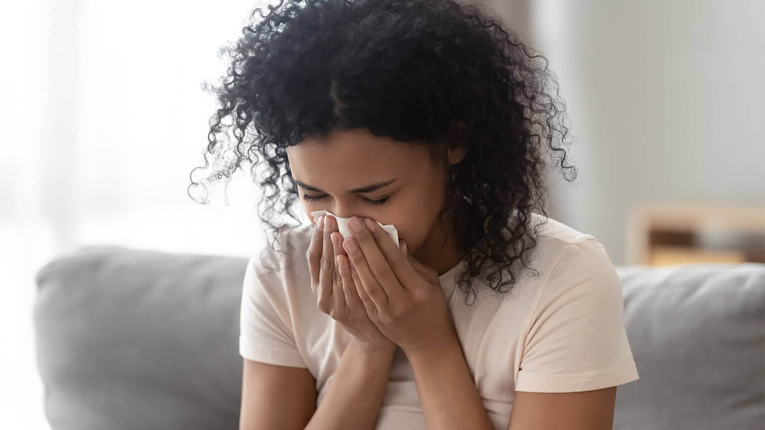 A young woman blowing her nose with a tissue