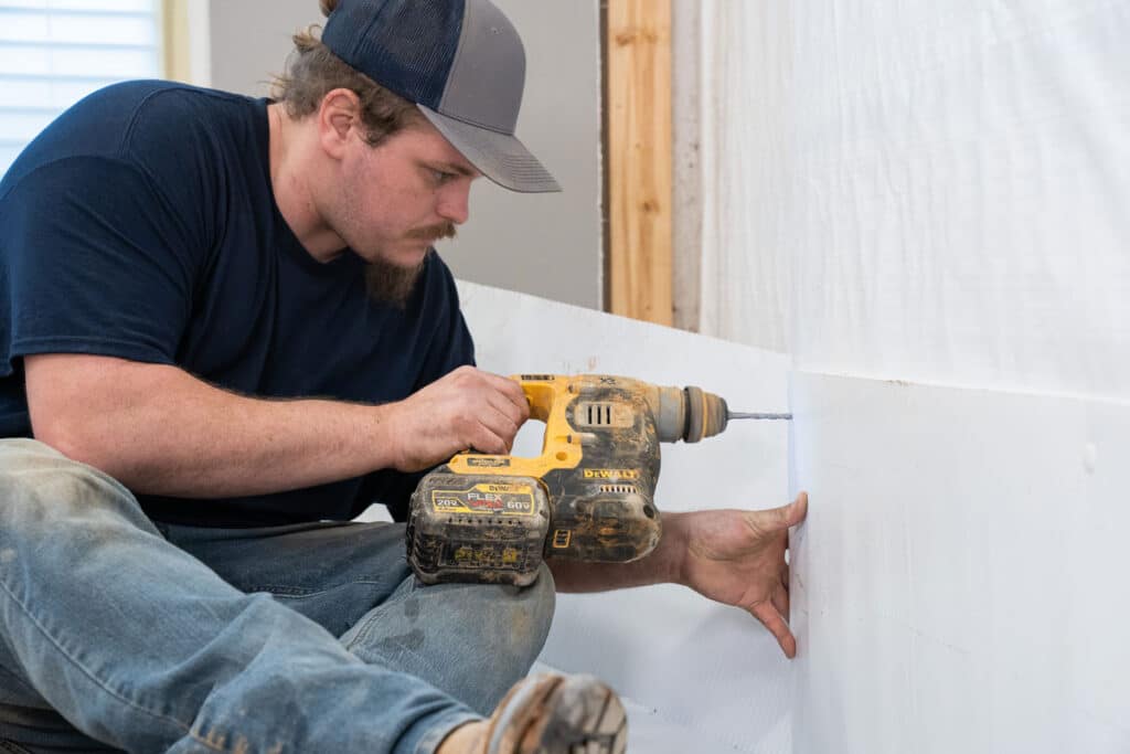 Man installing basement waterproofing vapor barrier