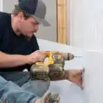 Man installing basement waterproofing vapor barrier