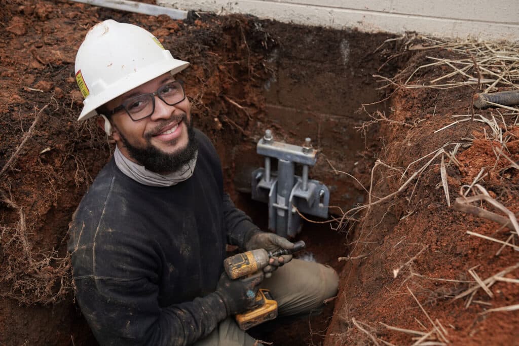 Foundation repair specialist installing outdoor helical piers