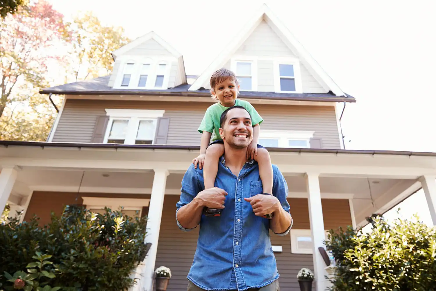 A man and a kid looking happy in front of a home