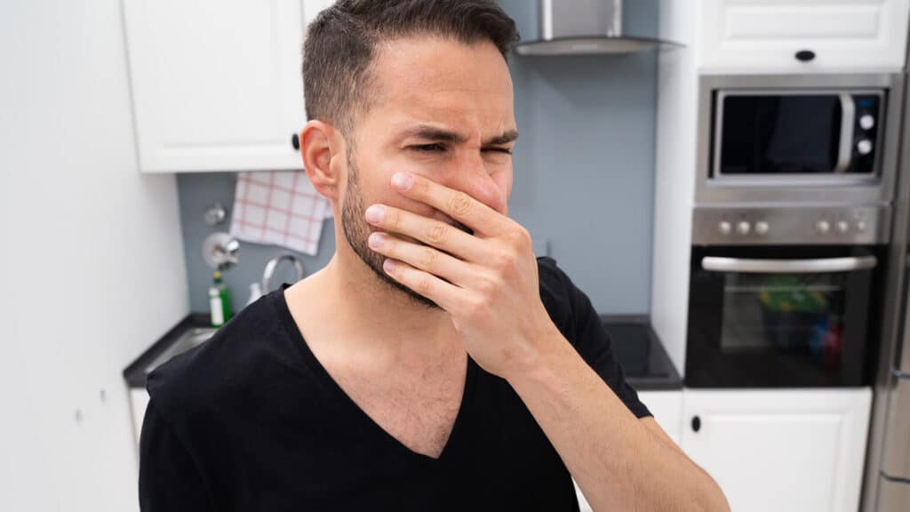 Man plugging his nose after smelling something
