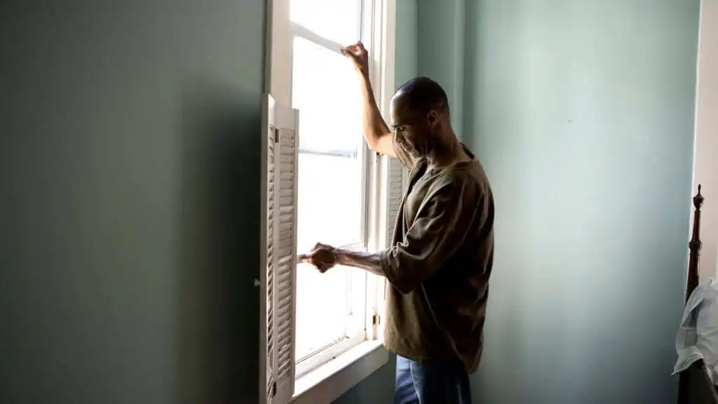 A man dealing with a stuck or jamming window in his home