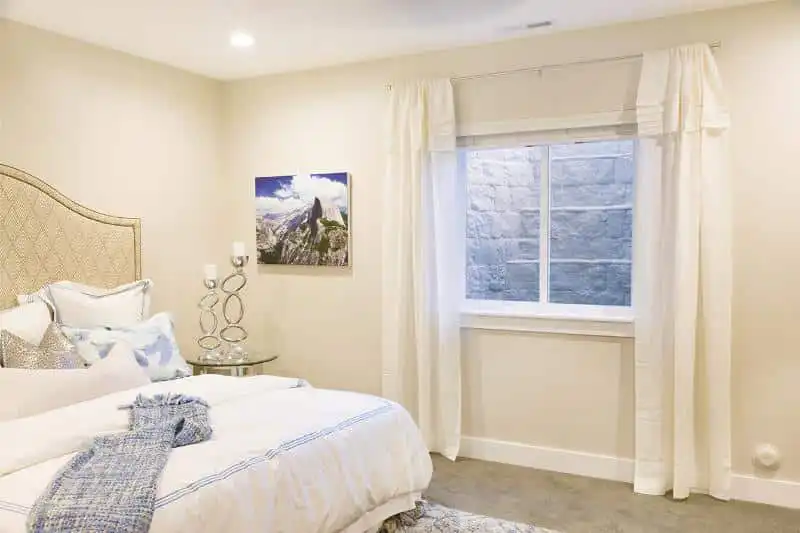 A fully finished basement bedroom with an egress window