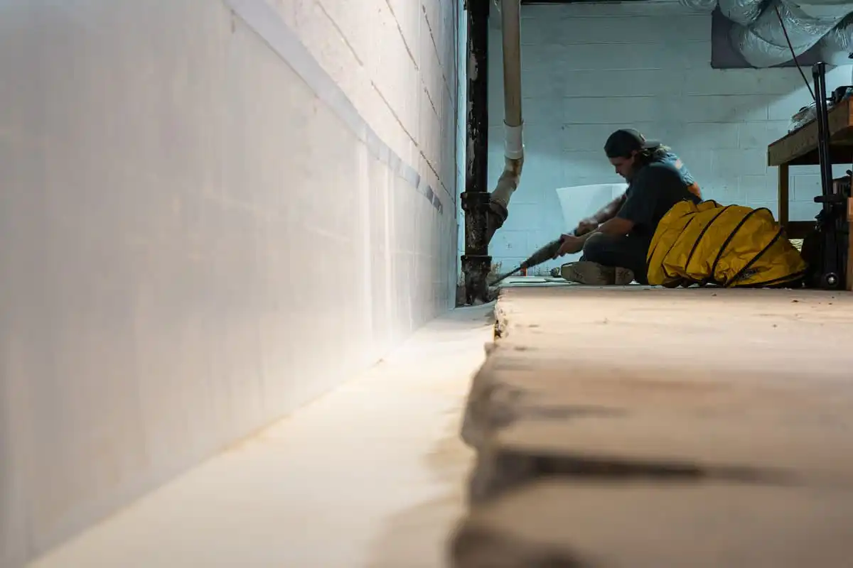 Man installing basement waterproofing drainage channels