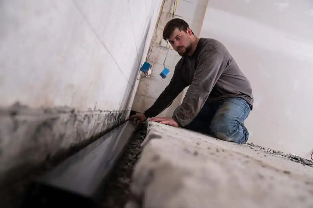 Man installing basement drainage channel pipe
