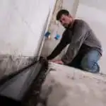 Man installing basement drainage channel pipe